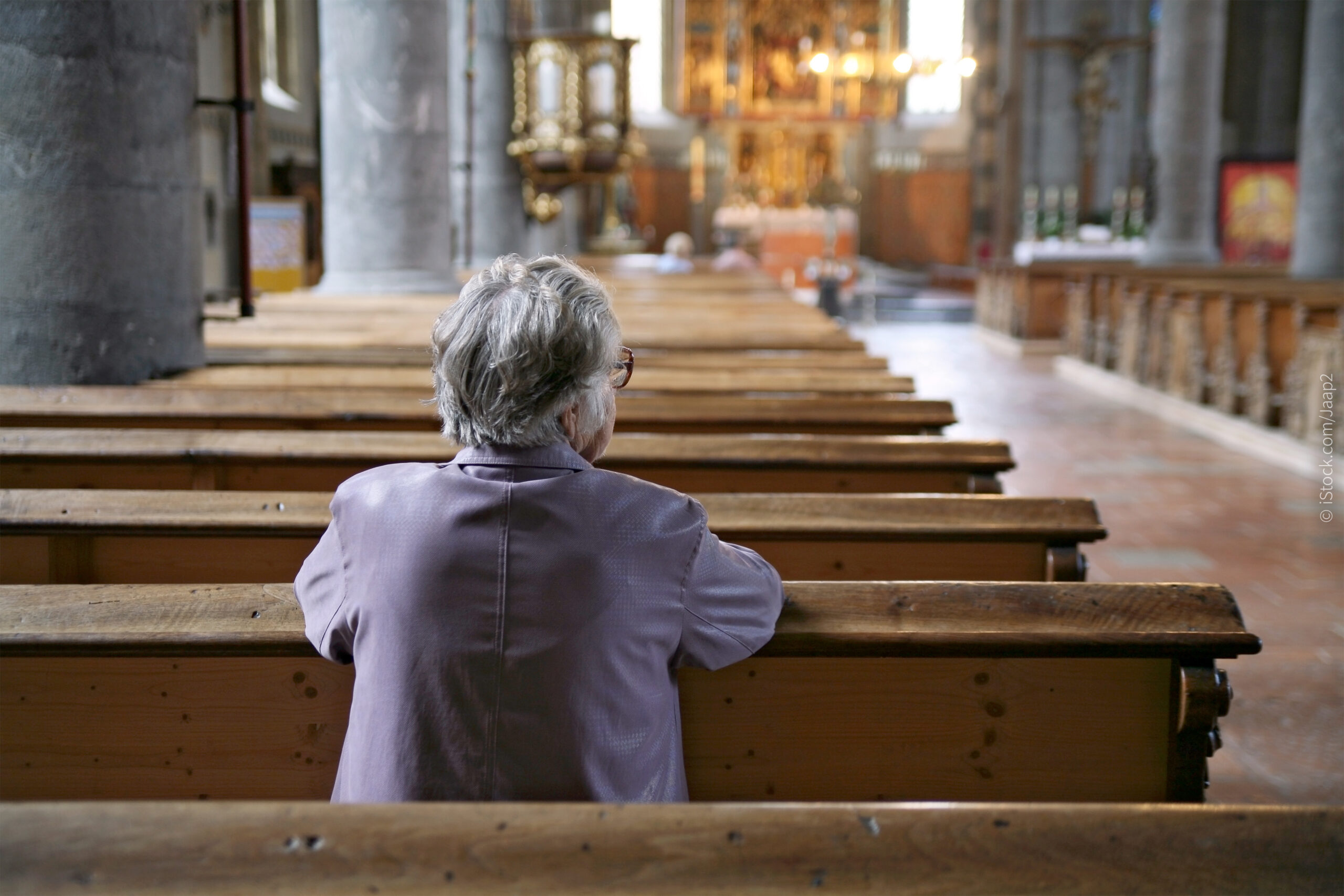 Ein alter Mensch sitzt in einer Kirchenbank