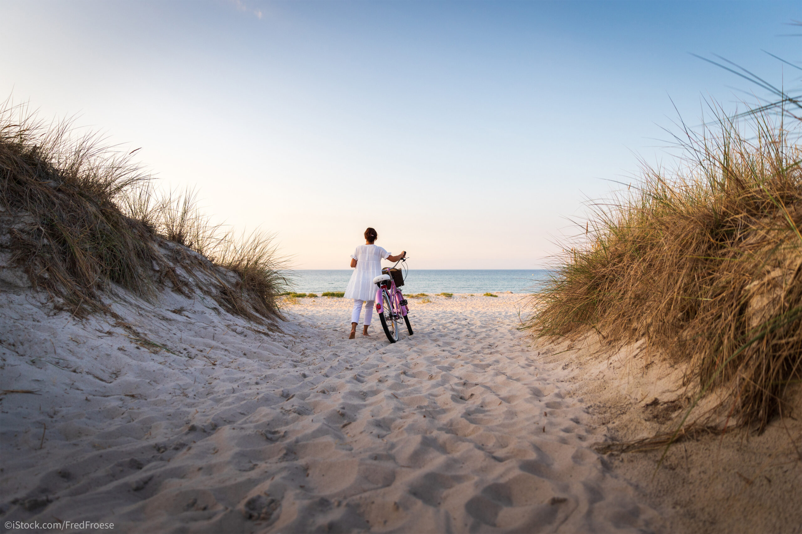 Eine Frau läuft mit einem Fahrrad durch Dühnen zum Strand. Blogbild zum Thema "Klagepsalmen Beispiele"