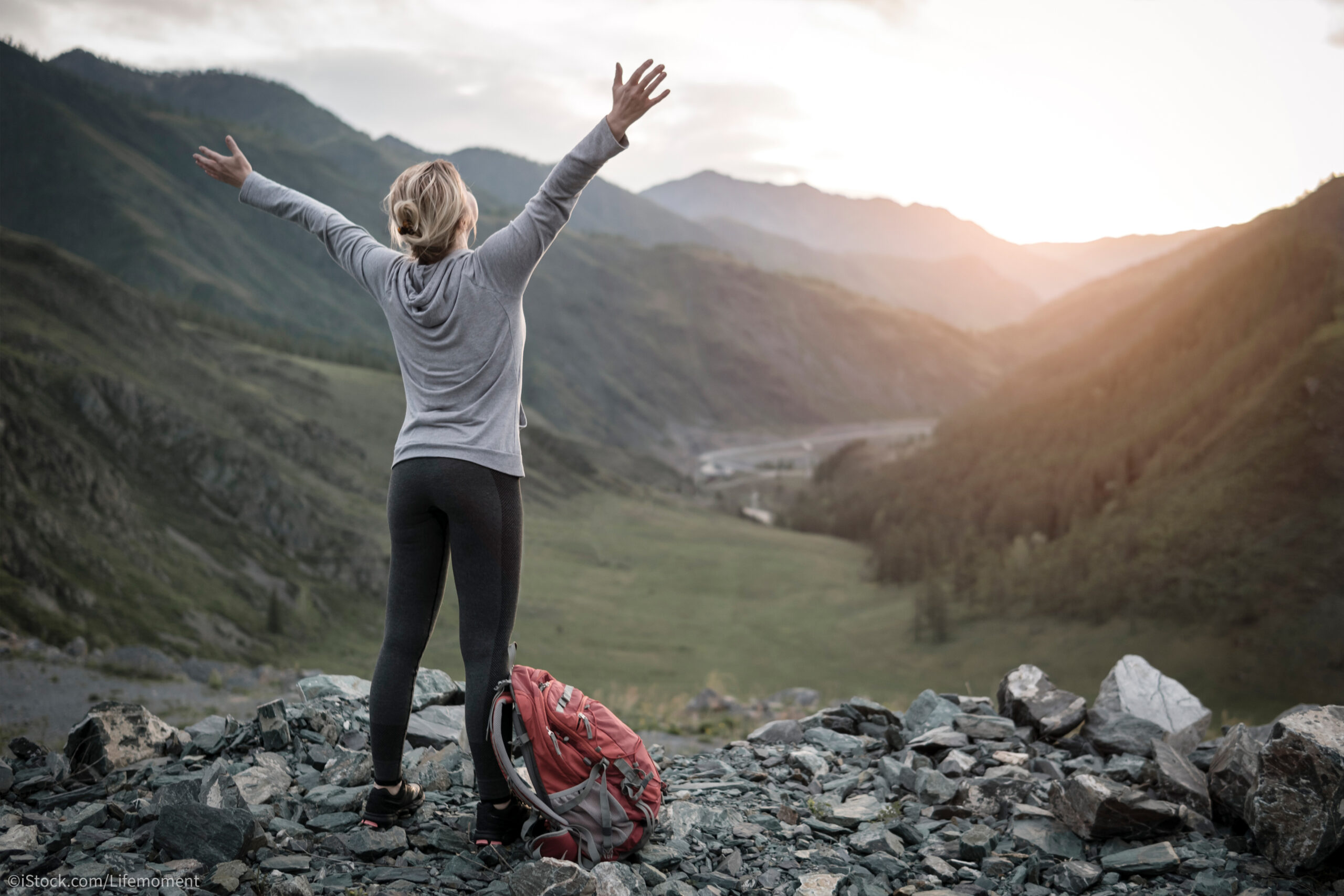 Eine Frau erfreut sich beim Wandern am Sonnenaufgang.