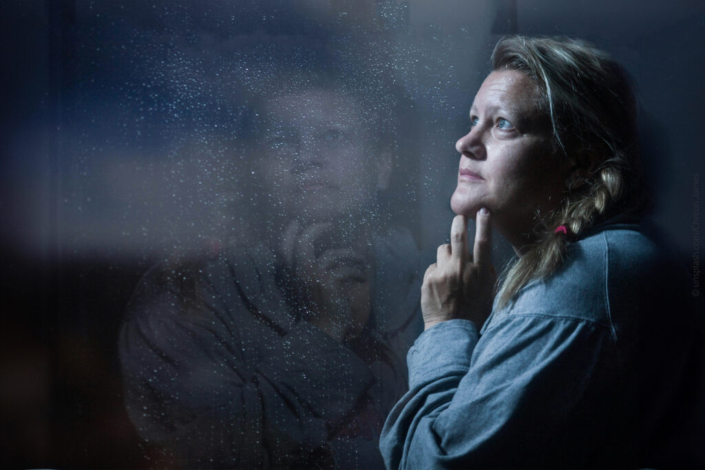 Eine Frau steht nachdenklich am Fenster